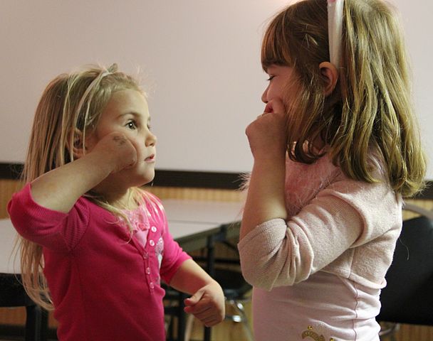 Two children practicing American Sign Language.